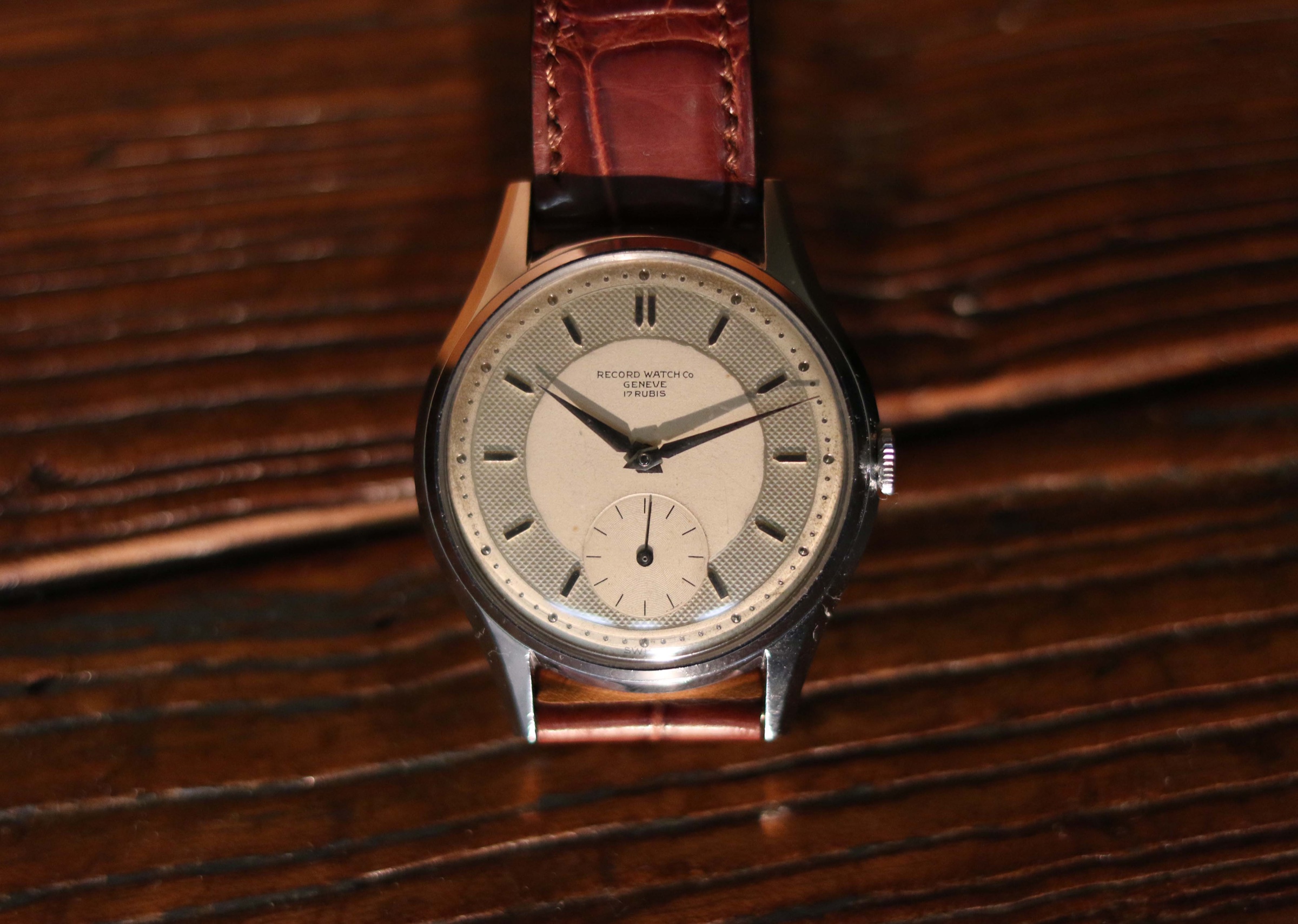 Front view of the Record Genève watch on a dark wooden surface